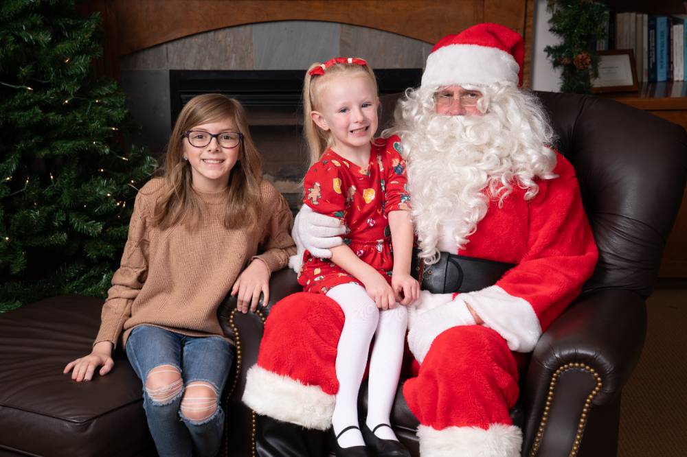 Two kids sitting with Santa at the event.